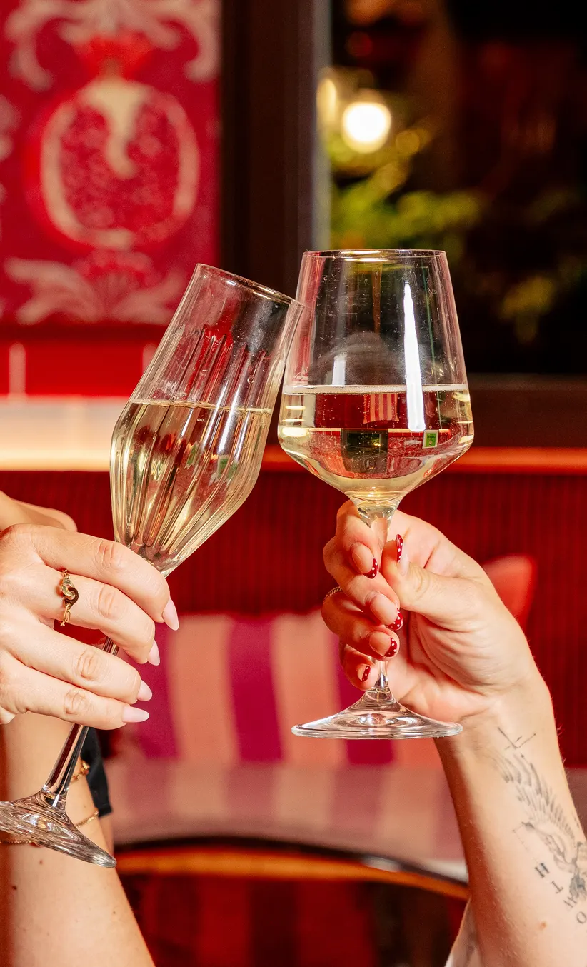 Deux verres de vin blanc qui trinquent dans la salle rouge de Scopertino