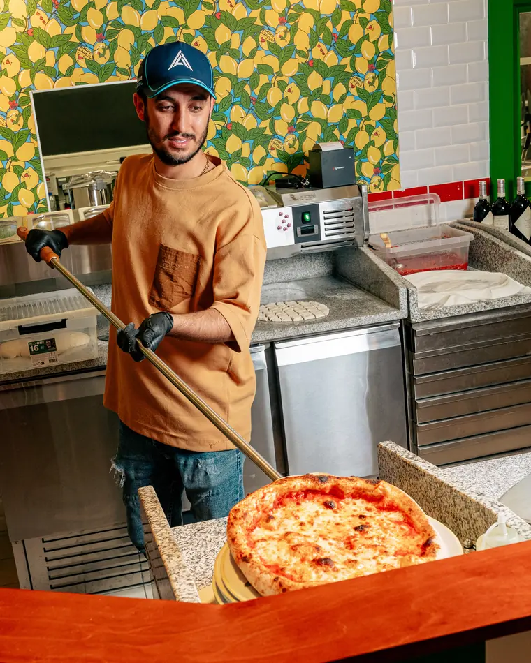 Le pizzaiolo de Scopertino sort une pizza du four à la pelle