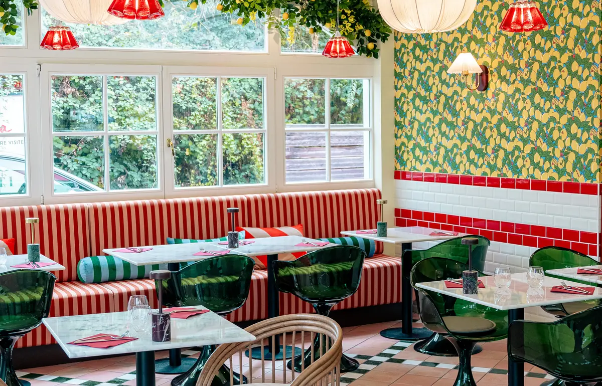 La salle de Scopertino : banquettes rayées rouges, fauteuils verts, papier peint aux citrons et grandes fenêtres